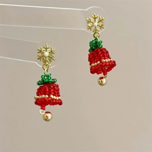 Detail of handcrafted Christmas tree earrings with red and green beads and golden snowflakes
