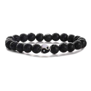 Black lava stone beads bracelet with a heart-shaped yin-yang charm on a white background