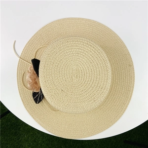 Close-up of woven straw sun hat with black ribbon bow and delicate fabric flower