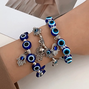 Detail van kralenarmbanden met blauwe Evil Eye-kralen en zilveren Hamsa-handhangers