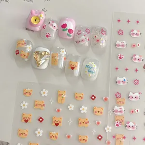 Close-up of pink cartoon nail stickers with bear and heart patterns on light background