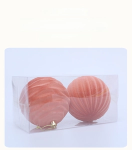 Macro shot of 10cm peach flocked Christmas balls with wave texture in a clear box
