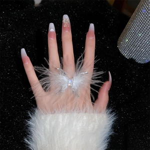 Detail of a white feather butterfly ring with crystals on a model's hand with black background