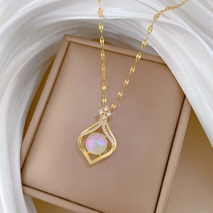 Nahaufnahme der goldenen Tropfenkette mit Opal und Diamanten auf einer Schmuckschatulle
