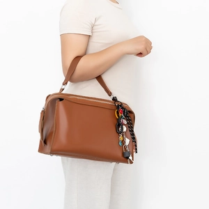 Borsa boston in pelle marrone con tracolla a pois e lucchetto in metallo indossata