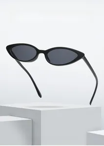 Close-up of black retro cat-eye sunglasses on a white geometric minimalist stone block