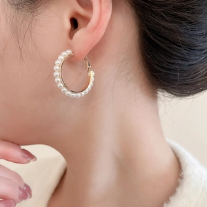 Nahaufnahme der goldenen Creolen mit kleinen weißen Perlen am Modell für eleganten Stil