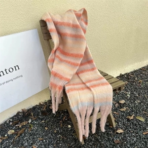 Detail of colorful striped winter scarf with long tassels on a wooden chair