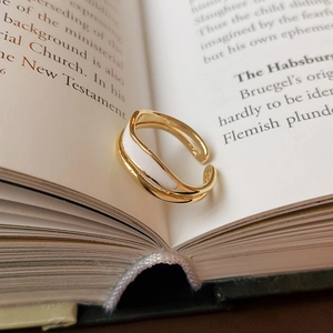 Detail of a wavy gold ring with white enamel inlay placed inside a book crease