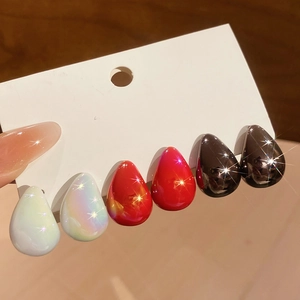 Detailed view of three pairs of teardrop earrings in iridescent white, red, and black finishes