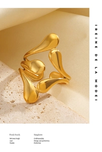 Artistic gold-plated drop-shaped ring with a sleek streamlined finish on silk background