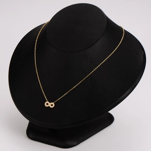 Golden stainless steel necklace with sparkling zircon infinity pendant on a black stand