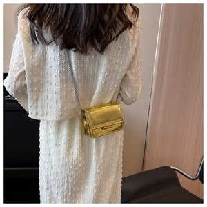 Detail of gold crocodile embossed mini square bag with elegant silver chain strap