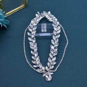 Detailed view of silver bridal forehead chain with leaf-shaped rhinestones on blue background