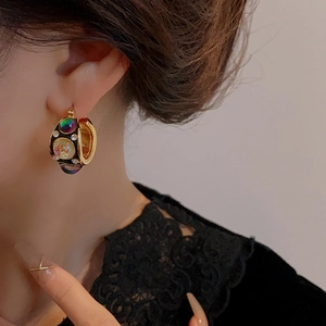 Close-up of vintage gold earrings with colorful gemstones and diamonds on a model
