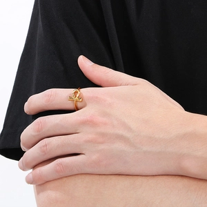 Detailed close-up of a golden Ankh cross ring featuring a polished metallic finish on a model