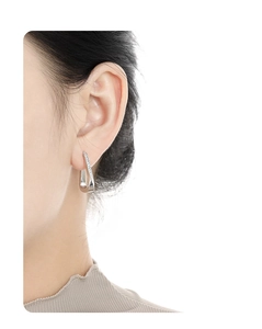 Close-up of a model wearing a geometric silver stud earring with micro-pave zircons