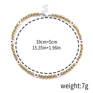 Detail of beaded necklace featuring gold beads and white pearls with red heart patterns