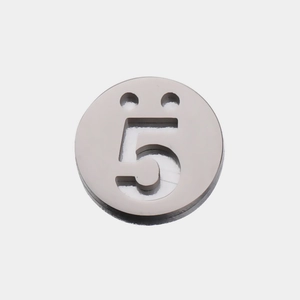 Détail macro d'un pendentif rond en acier argenté avec chiffre 5 découpé et deux trous