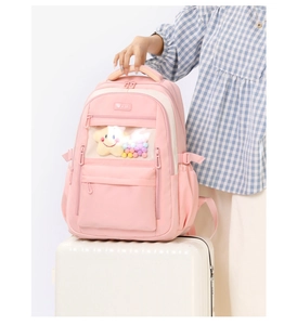 Pink nylon school backpack on white luggage featuring a clear front pocket and top handle
