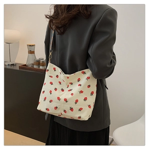 Detail of strawberry print corduroy tote bag featuring a decorative wide shoulder strap