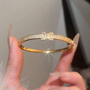 Macro detail of gold plated cubic zirconia bangle featuring classic vintage logo buckle
