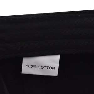 Macro detail of the 100% cotton washing label on a black baseball cap interior