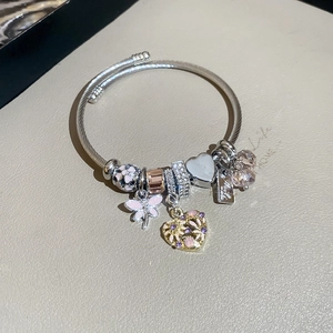 Close-up of silver braided bracelet featuring pink enamel floral and diamond heart charms