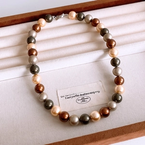 Detail einer mehrfarbigen Perlenkette mit champagner- und smaragdfarbenen Perlen in Geschenkbox