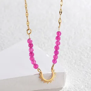 Macro shot of gold stainless steel beaded necklace with pink stones and sunburst pendant