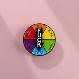Macro view of a colorful spinning enamel pin with rotating black pointer and metal details