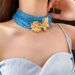 Detail of multi-strand blue seed bead necklace with gold butterfly and flower clasp