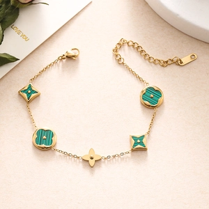 Close-up of gold double-layer chain bracelet with green flower charms and lobster clasp