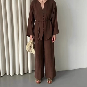 Dettaglio del tessuto marrone cioccolato su camicia elegante con scollo a V e pantaloni