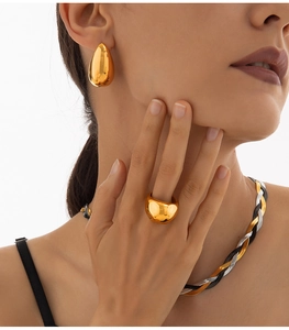 Macro detail of mixed-metal snake chain necklace with gold earrings and ring set