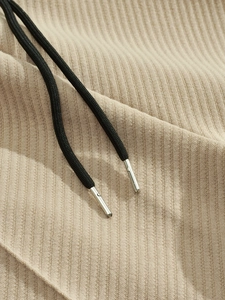 Macro del tessuto a costine beige con coulisse nera e punte in metallo argentato lucido