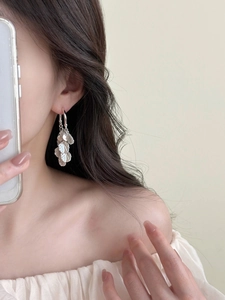Detailed view of silver petal tassel earrings with textured metallic finish on model