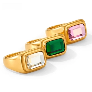 Detailed macro shot of three minimalist gold rings set with green, white, and purple gemstones