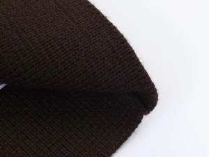 Gros plan du tissu en maille côtelée marron foncé sur le cardigan en tricot élégant