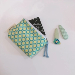 Macro detail of floral cotton storage pouch with light blue rope zipper and woven label