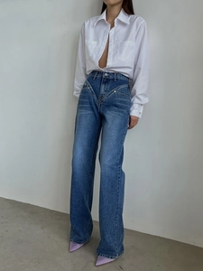 Detail of high-waisted indigo jeans featuring a unique V-shaped stitched waistline design