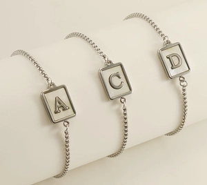 Detail view of rectangular shell alphabet pendants A, C, D on stainless steel chains