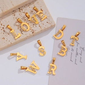 Détail de pendentifs lettres en acier inoxydable plaqué or 18k avec zircons
