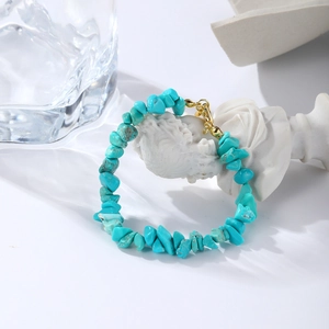 Detailed macro shot of turquoise stone beads with a gold lobster clasp and extension chain
