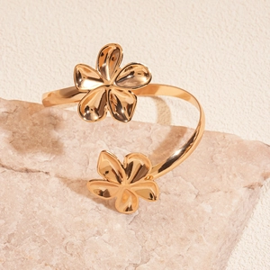 Poliertes goldfarbenes Blumen-Armreif mit zwei Blütenmotiven auf Steinuntergrund
