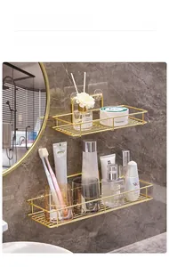 Detail of gold metal wall-mounted bathroom shelves with adhesive pads and toiletries