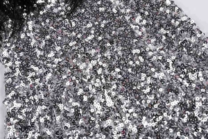 Détail de paillettes argentées avec bordure en plumes noires sur une robe de soirée