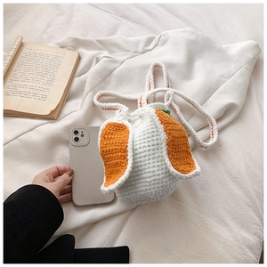 Detail of handmade crochet bucket bag featuring carrot design and woven shoulder strap