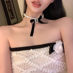 Elegant pearl choker necklace featuring black velvet bow and crystal-encrusted gemstone