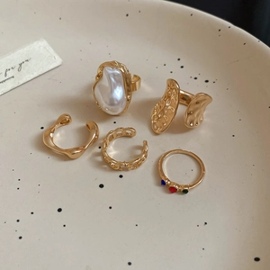Detail of luxury gold alloy jewelry set featuring colorful stones and pearls on ceramic plate